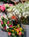 Buckets of assorted flowers including roses and lisianthus displayed at a market stall.