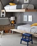 Gray bedroom with two hanging wooden bunk beds, yellow pillows, a blue step stool, and a guitar in the corner.