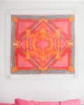 Abstract geometric painting in pink, orange, and gray above a pink sofa with matching cushions.