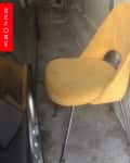 Worn yellow chair with metal legs placed in a narrow garage space.