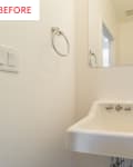 Small bathroom corner with a wall-mounted sink, mirror, towel ring, and light switches.