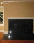 Empty room with beige walls, black tiled fireplace, and wooden floor.
