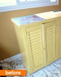 Yellow shutter-style cabinet on a floral drop cloth, labeled "before."