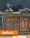 Dark wooden dresser with ornate carvings and multiple drawers in a workshop setting.