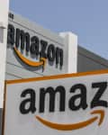 Amazon logo on building facade with large sign in foreground.