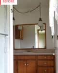 Bathroom with wooden vanity, large mirror, hanging lights, and lace curtains.