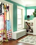 Living room with teal walls, colorful curtains, white fireplace, bookshelves, and a geometric rug.