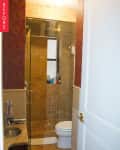 Small bathroom with glass shower, red patterned wallpaper, beige tiles, and a granite countertop with a sink.