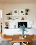 Living room with white shelves, TV, decor items, and a wooden coffee table with a vase of greenery.