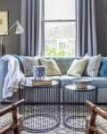 Cozy living room with a light blue sofa, patterned pillows, round wire coffee tables, and a blue lamp.