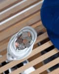 Baseball cap and ceramic dish with coins on a wooden slatted surface.