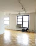 Empty room with parquet flooring, large windows, ceiling fan, and track lighting.