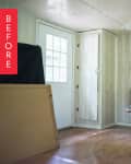 Cluttered room with wood paneling, a microwave on a shelf, a barrel, and a door with a window.