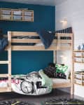 Kids' room with wooden bunk bed, blue accent wall, white wardrobe, and storage bins. Bedding features playful patterns.