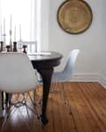 Dining area with dark wood table, white chairs, tall candlesticks, and a large decorative wall plate.