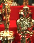 Golden Oscar statuettes displayed on a red surface.