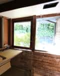 Unfinished kitchen space with exposed wooden walls, a window, and a countertop with a geometric-patterned book.