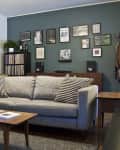 Living room with gray sofa, patterned pillows, wooden coffee table, and a gallery wall on a dark green accent wall.