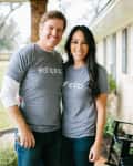 Couple in matching gray "#shiplap" shirts standing on a porch with black rocking chairs.