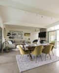 Open-plan living and dining area with yellow chairs, a wooden table, large artwork, and sliding glass doors to a patio.
