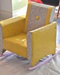 Yellow and gray vintage rocking chair on a drop cloth in a room with wooden floor.