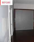 Empty room with dark wood floors, gray walls, a large gray partition, and a paper lantern ceiling light.