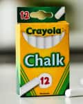 Box of Crayola chalk with 12 white sticks on a table.