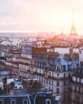 Paris cityscape with historic buildings and the Eiffel Tower at sunset.