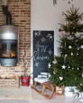 Cozy living room with a brick fireplace, Christmas tree, sled, and festive decor.