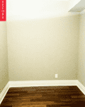 Empty room with beige walls, dark wood flooring, and white baseboards.