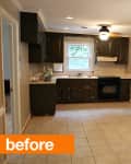 Spacious kitchen with dark cabinets, tile floor, and a small island, featuring a window and ceiling light fixture.
