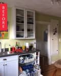 Cluttered kitchen with green walls, open dishwasher, stainless steel appliances, and a dog bed on the floor.