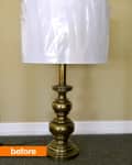 Brass table lamp with a white plastic-wrapped shade on a carpeted floor.
