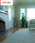 Living room with large window, gray sofa, white armchair, green plant, and fireplace.