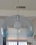 Clear glass pendant light fixture with a visible bulb hanging from the ceiling in a modern room.