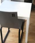 White table with a gray chair marked with the number 8 on a wooden floor.