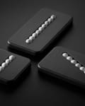 Three black rectangular objects with diagonal slots, each containing a row of silver spheres.