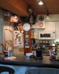 A cluttered kitchen with wood accents and white particleboard cabinets
