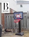 Outdoor basketball hoop in a backyard with a wooden fence and potted plants.