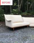 Beige sectional sofa with wooden legs on gravel, surrounded by trees.