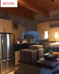 Kitchen with wooden ceiling, pendant lights, stainless steel fridge, and countertops cluttered with boxes and storage bins.