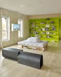 Loft living room with exposed brick, lime green bookshelf, modern black bench, and low white sofa.