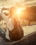 Woman sitting on a ledge photographing the Colosseum at sunset.