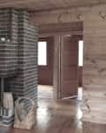 Brick fireplace in a wooden room with a woven basket and open doorway.