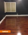 Empty room with dark walls, wooden floor, and a window with closed blinds.