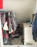 Cluttered closet with hanging clothes, shoes on racks, and a dresser with toiletries.