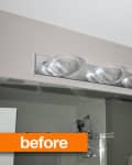 Bathroom vanity light fixture with five clear glass shades above a mirror.