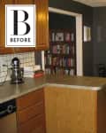 Kitchen with wooden cabinets, black dining table, wall clock, and bookshelf in the background.