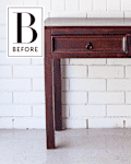 Dark wooden console table with two drawers against a white brick wall.