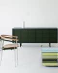Modern living room with a green sideboard, glass coffee table, minimalist chair, and sleek floor lamp.